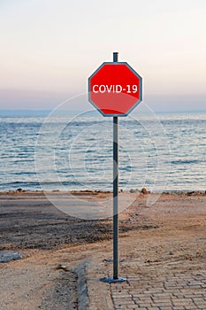 Stop sign with words covid-19 on beach near sea in Italy. Concept - unemployment in tourism during global epidemic of covid-19