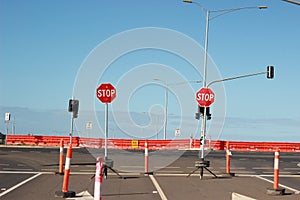 Stop signs and various warning signs warning oncoming traffic of the end of the road on a highway still under construction in