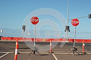 Stop signs and various warning signs warning oncoming traffic of the end of the road on a highway still under construction in