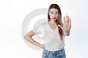 Stop, stay back. Serious and confident girl stretch hand to say no, prohibit, keep social distancing on pandemic, making photo