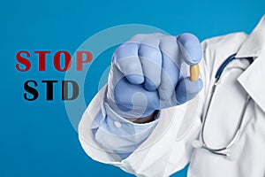 STOP STD. Doctor holding suppository on blue background, closeup