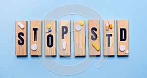 The STOP STD is written on wooden blocks on a light blue table near the pills. Medical concept