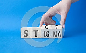 Stop and Stigma symbol. Concept words Stop and Stigma on wooden cubes. Beautiful blue background. Businessman hand. Business and photo