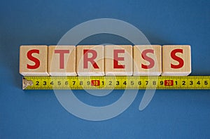 Stop stress and be health symbol. Wooden cubes with the word `stress` behind yellow ruler. Beautiful blue background.