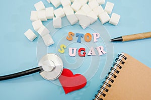 Stop sugar, text colored letters. The concept of offering diets and eating less sugar for health. Cubes of white sugar, a notebook