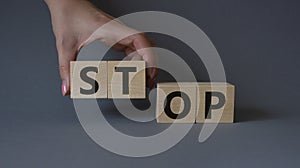 Stop symbol. Concept word Stop on wooden cubes. Businessman hand. Beautiful grey background. Business and Stop concept. Copy space