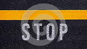 Stop text written and yellow line on the road in middle of the asphalt road, Stop word on street
