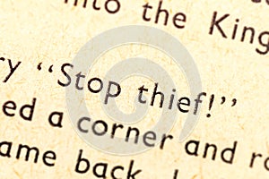 Stop thief! Single text line focus, words in an old book dramatic macro extreme closeup Literature thievery, burglary, robbery photo