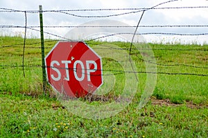 Stop Traffic Sign on a barbwire fence in a field.