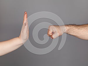 Stop violence against women campaign. Woman using hand palm to stop man`s punch from attack isolated, on gray background