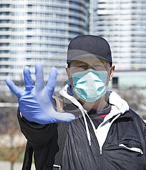 Stop the virus and epidemic diseases. Man in blue medical protective mask and medical gloves showing gesture stop. Health