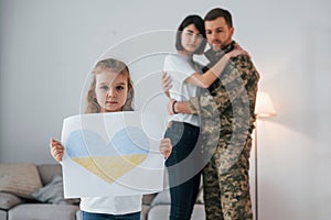 Stop war in Ukraine conception. Soldier in uniform is at home with his wife and daughter