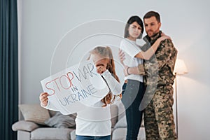 Stop war in Ukraine conception. Soldier in uniform is at home with his wife and daughter