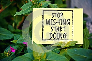 Stop wishing start doing quote written on paper on green garden background. Taking action for achievement in business or life