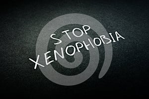 Stop xenophobia handwritten sign on black paper.