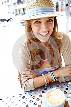 Stopping off for a cup of coffee. A happy young woman smiling at the camera while sitting at a sidewalk cafe in the city