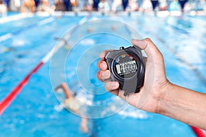 Stopwatch holding on hand with competitions of swimming.