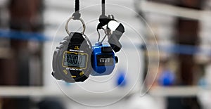 A stopwatch and a whistle hanging by their lanyards in a gym.