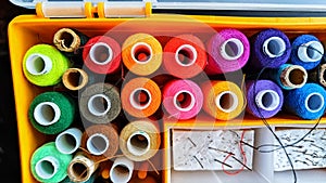 Storage box with spools of multi-colored threads, sewing needles. Storage system for sewing needlework at home
