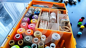 Storage box with spools of multi-colored threads, sewing needles. Storage system for sewing needlework at home