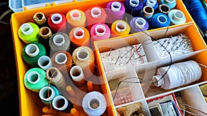 Storage box with spools of multi-colored threads, sewing needles. Storage system for sewing needlework at home