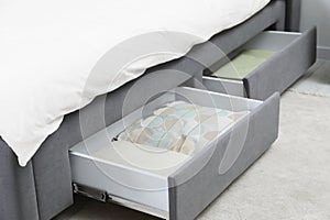 Storage drawers with bedding under modern bed in room