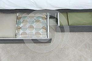 Storage drawers with bedding under modern bed in room, above view