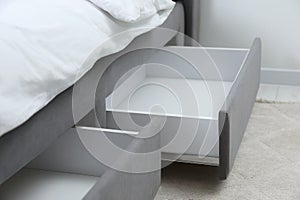 Storage drawers for bedding under modern bed in room, closeup