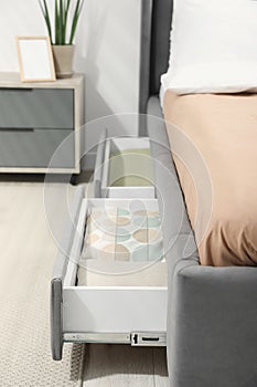 Storage drawers with bedding under modern bed in room, closeup