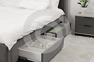Storage drawers with bedding under modern bed in room. Space for text