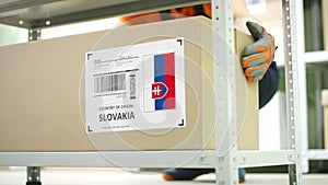 Worker takes away a carton with goods from Slovakia on the shelf