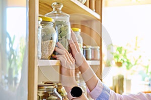 Storage of food in the kitchen in pantry, woman& x27;s hands with a can