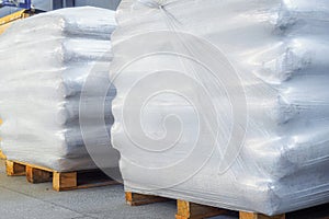 Storage of packaged goods or cargo in warehouse. On wooden pallets there are bags of cement wrapped with polyethylene
