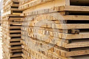 Storage of piles of wooden boards on the sawmill. Boards are stacked in a carpentry shop. Sawing drying and marketing of