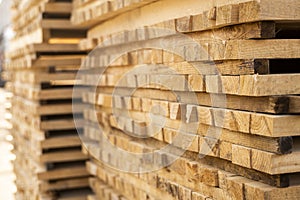 Storage of piles of wooden boards on the sawmill. Boards are stacked in a carpentry shop. Sawing drying and marketing of