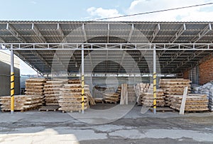 Storage and production of wooden stick cuttings for garden tools. Warehouse of household goods under a canopy on pallets