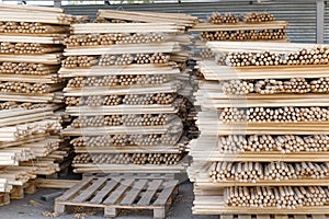 Storage and production of wooden stick cuttings for garden tools. Warehouse of household goods under a canopy on pallets