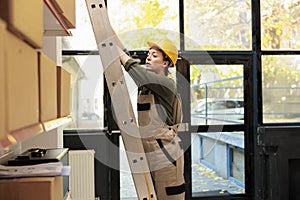 Storage room manager standing on ladder in warehouse