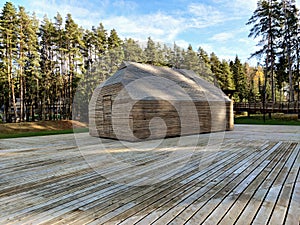 Storage shed stands on a wooden terrace. Minimalistic shed and patio made of similar wooden planks