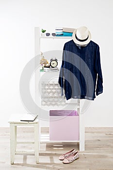 Storage system in the bedroom. Shelving with boxes, alarm clock, books, for small items and with dress hanging on a hanger