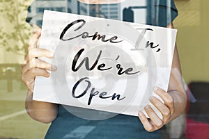 Store owner holding open sign broad through  glass window and ready to service. opening after lockdown quarantine