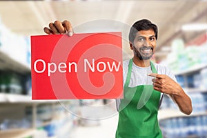 Store owner presenting open now sign