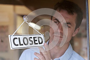 Store Owner Turning Closed Sign In Shop Doorway