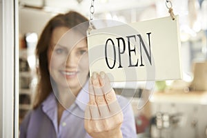 Store Owner Turning Open Sign In Shop Doorway