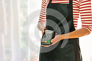 Store worker requesting for payment over nfc technology. Store worker holding pos terminal photo