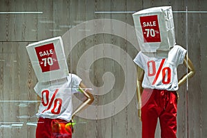 Storefront with discount concept. Manikins in a T-shirt with paper bags with sign `-70%`.