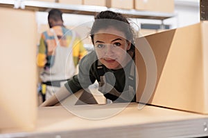 Storehouse employee taking out cardboard box from shelf