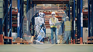 Storeman checking operation of robot pulling a cart