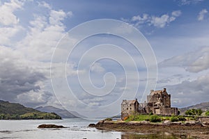 Storied Eilean Donan Castle presides over a loch against lush Highland greenery under expansive sky photo