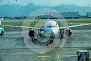 Storm at the airport. View of the airplane through rain drops. Waiting at the airport due to delay. Travel